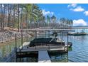 View of covered boat dock with boat in a peaceful lake setting on a sunny day at 7875 Robin Rd, Cumming, GA 30041