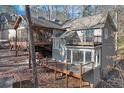 Exterior view of two-story home featuring multiple decks, screened porch, and mature trees at 7875 Robin Rd, Cumming, GA 30041