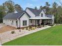 Beautiful modern farmhouse boasts a side-entry garage, landscaped front yard, and welcoming covered porch at 3911 Peeksville Rd, Locust Grove, GA 30248