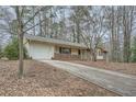 View of the home's facade, long driveway and attached garage with a well-manicured lawn at 2102 Red Berry Sw Ln, Marietta, GA 30008