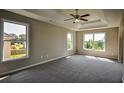 Spacious main bedroom featuring tray ceiling, fan, and multiple windows for ample natural light at 907 Southfork Dr, Loganville, GA 30052