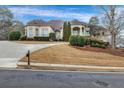 Beautiful home with circular driveway, well-manicured lawn and bushes, and neutral-colored facade at 1069 Eagles Brooke Dr, Locust Grove, GA 30248