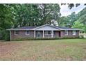 Quaint brick home featuring a covered front porch with beautiful landscaping at 5555 Woodland Dr, Douglasville, GA 30135