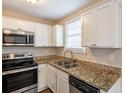 Corner view of a kitchen highlighting granite countertops, stainless appliances, and white cabinetry at 3499 Villa Se Cir, Atlanta, GA 30354