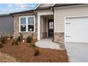 Close up of house with stone accents, two-car garage and a beautiful landscaped yard at 1723 Juniper Berry Way, Loganville, GA 30052