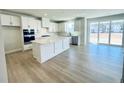 Open concept kitchen featuring stainless appliances, white cabinets, and large island with doors to the backyard at 718 Crossroad Ct, Powder Springs, GA 30127