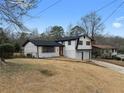 View of home with white brick, black trim, and an attached two-car garage in a fenced yard at 2385 Tiffany Pl, Decatur, GA 30035