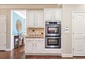 Stylish kitchen featuring stainless steel double ovens, tile backsplash and wooden floors at 3830 Deer Run Dr, Cumming, GA 30028