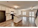 Bright, open-concept kitchen featuring an island, granite counters, white cabinets, and hardwood floors at 1797 Old Dogwood, Jonesboro, GA 30238