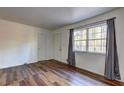 Cozy bedroom featuring a window, new wood-look flooring, fresh paint, and a doorway to an adjacent room at 5990 Mallory Rd, South Fulton, GA 30349