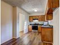 Cozy kitchen featuring wood cabinets, stainless steel appliances, and sleek, dark countertops with wood flooring at 5990 Mallory Rd, South Fulton, GA 30349