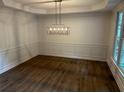Elegant dining room with modern chandelier, wainscoting, and hardwood floors at 9137 Loxford St, Lithia Springs, GA 30122