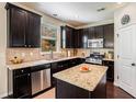 Modern kitchen with stainless steel appliances, granite countertops, and dark wood cabinetry at 1919 Glencliff Way, Sugar Hill, GA 30518