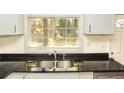 Close-up of a black granite kitchen counter with stainless steel sink and white cabinets at 2413 Hillside Ave, Decatur, GA 30032