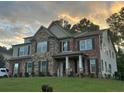 Two-story brick and stone home with a gable roof, covered front porch, and lush green lawn at 2304 Northglenn Ct, Conyers, GA 30013