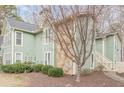 Exterior view of a condo featuring stone accents, green siding, and a well-kept lawn at 3205 Canyon Point Cir, Roswell, GA 30076