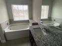 Bright bathroom with a soaking tub, dark vanity with granite counters, and a large window at 5021 Falcon Pt, Douglasville, GA 30135