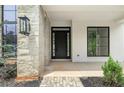 Close-up of front door showcasing stone accents, modern black door and stylish lantern lighting at 401 Lynne Cir, Alpharetta, GA 30009