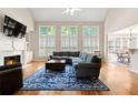 Inviting living room with fireplace, tall windows, and hardwood floors at 7215 Gresham Trce, Cumming, GA 30040