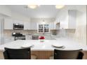 Bright kitchen features white cabinets, quartz countertops, stainless appliances, and breakfast bar at 3705 Windy Hill Se Dr, Conyers, GA 30013