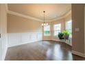 Formal dining room with dark hardwood floors, decorative molding, and modern chandelier at 1187 Kingston Hill Dr, Loganville, GA 30052