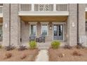 Inviting covered front porch with rocking chairs, planters, and brick columns at 581 Brashy St, Woodstock, GA 30188