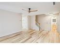 Bright living room featuring wood floors, a modern ceiling fan, and staircase with white risers and natural wood handrail at 3815 Glen Laurel Ct, Cumming, GA 30040