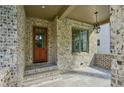 Inviting front porch featuring brick detail, stone flooring, and stylish lighting fixture at 114 Terrace Ne Dr, Atlanta, GA 30305