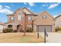 Attractive brick and stone home with a well-maintained lawn, mature tree, and a two-car garage at 4808 Albany Way, Atlanta, GA 30331