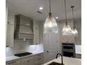 Modern kitchen with stainless steel appliances, stone countertops, custom vent hood and designer pendant lighting at 866 Lakemont Dr, Canton, GA 30114