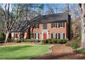 Charming two-story brick home with a vibrant green lawn, complemented by mature trees at 2170 Azalea Dr, Roswell, GA 30075