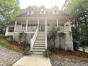 Charming two-story home featuring a welcoming front porch with stairs and manicured shrubs and trees at 525 S Lost Lake Cv, Villa Rica, GA 30180