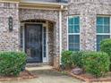 Close up of the glass front door with sidelights, brick archway, and manicured landscaping at 600 Lockerbie Ter, Mcdonough, GA 30252
