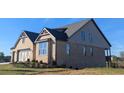 Side view of a brick and siding home showcasing large windows and professional landscaping at 2235 Windsor Bluffs Dr, Cumming, GA 30041