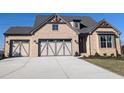 Charming brick home with a three-car garage, striking architectural details, and a concrete driveway at 2235 Windsor Bluffs Dr, Cumming, GA 30041