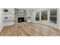 Cozy living room with a brick fireplace, hardwood floors, and a large bay window with wooded views at 5548 Martina Way, Atlanta, GA 30338