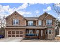 Charming two-story brick home with a welcoming front porch and well-maintained front yard on a sunny day at 6124 Locklear Way, Douglasville, GA 30134