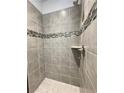 Modern shower featuring gray tile, decorative accent tiles, and a built-in shower caddy for a spa-like experience at 3392 Milan Ct, Douglasville, GA 30135