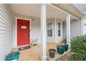 Inviting front porch featuring a bright red door, white columns, and decorative potted plants at 40 Berkshire Run, Covington, GA 30016