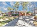 Inviting brick home showcases a covered carport, lush landscaping, and a lengthy driveway leading to the residence at 2187 Freydale Se Rd, Marietta, GA 30067