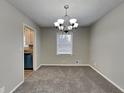 Cozy dining room with carpet flooring, a classic chandelier, and a view into the adjacent kitchen at 1848 Englewood Way, Snellville, GA 30078