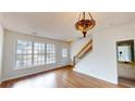 Spacious living area with hardwood floors, a decorative light fixture, and a staircase at 65 Devonshire Dr, Alpharetta, GA 30022