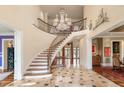 Grand foyer with curved staircase, elegant chandelier, and beautiful marble tile flooring at 4266 Woodland Brook Se Dr, Atlanta, GA 30339