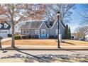 Charming home with mature tree in yard, featuring a quaint front porch, and a cheerful turquoise front door at 449 South Hill St., Buford, GA 30518