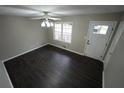 Well-lit bedroom features dark wood-look laminate flooring, a window, and a white door with brushed nickel hardware at 4973 Horton Pl, Douglasville, GA 30135