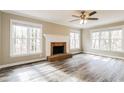 Bright living room features a cozy brick fireplace, large windows, and modern wood-look flooring at 145 Price Hills Ct, Sugar Hill, GA 30518