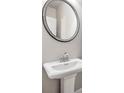Elegant bathroom featuring a pedestal sink and round mirror at 253 Beau St, Lilburn, GA 30047