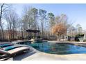 Backyard oasis showcasing a luxurious pool, stone surround, pergola, lounge chairs, and privacy fencing at 4095 Copper Leaf Ln, Cumming, GA 30040