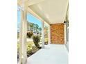 Covered front porch with white columns, brick accents, and manicured landscaping at 6242 Marbut Farms Ln, Lithonia, GA 30058
