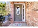 A welcoming front door with an oval window is framed by brick and a charming floral doormat at 3263 Tomeh Way, Tucker, GA 30084